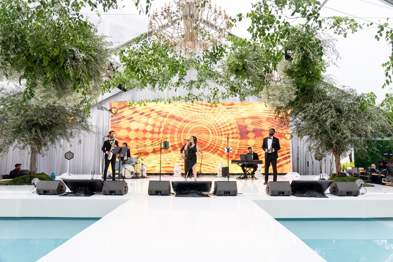 Sunny Jazz Band performing at the Beverly Hilton outdoor ballroom with chandelier, greenery, and reflecting pools