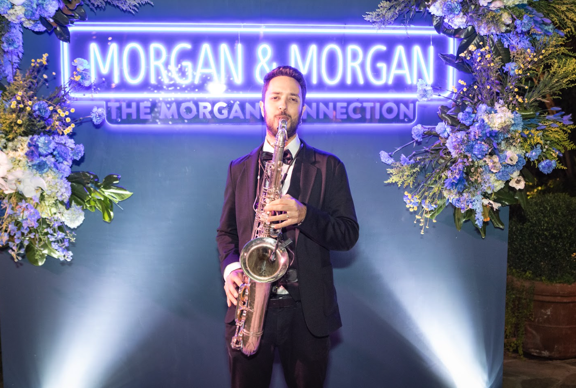 Sunny Jazz Band saxophonist performing at Morgan and Morgan corporate event in front of The Morgan Connection backdrop