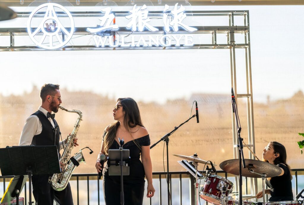 Sunny Jazz Band trio with saxophonist, vocalist, and drummer performing live at a branded corporate function in Los Angeles